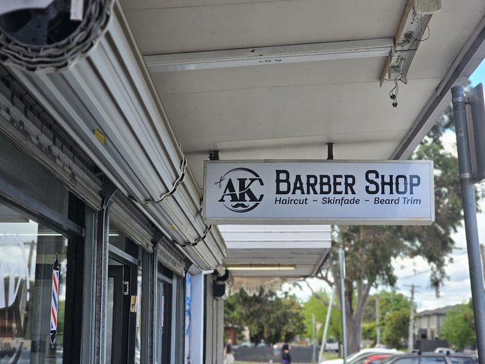 AK Barber Shop — Double-sided projecting lightbox mounted under the verandah by Top1 Signs, Melbourne